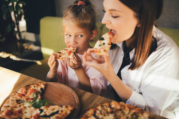 mother and daughter eat pizza in a cafe. - vacations two generation family caucasian friendship imagens e fotografias de stock