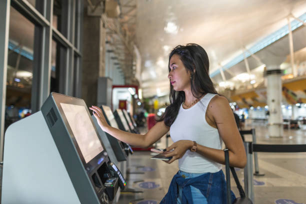 young woman using self service check in at the airport - self service stockfoto's en -beelden