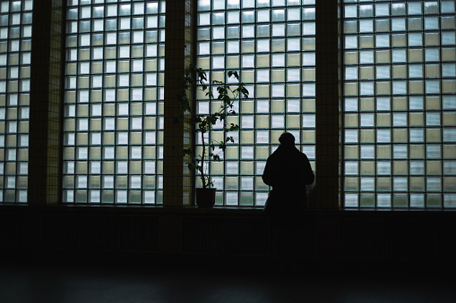 Silhouette of a man against the background of a large window which is in square shape