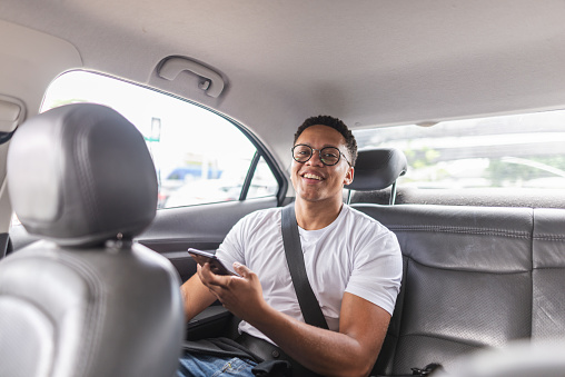 Male passenger using laptop in the backseat of a car