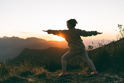 Woman doing yoga at sunset in the mountains