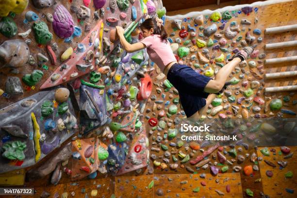 Female Athlete Climbing Bouldering Wall Hanging By Arms Stock Photo - Download Image Now