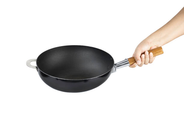 istock Hand holding cast iron pan with wooden handle isolated on white background with clipping path. 1441785657