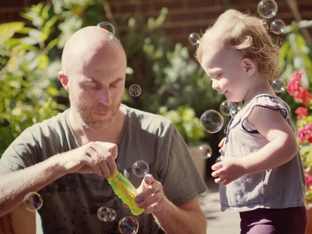 istock Young girl and father playing with bubbles 1441799489