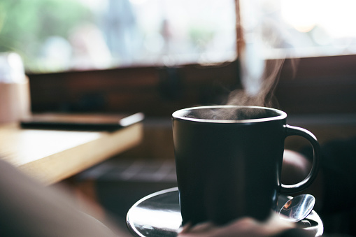 Hot cup of coffee on blurred coffee shop background