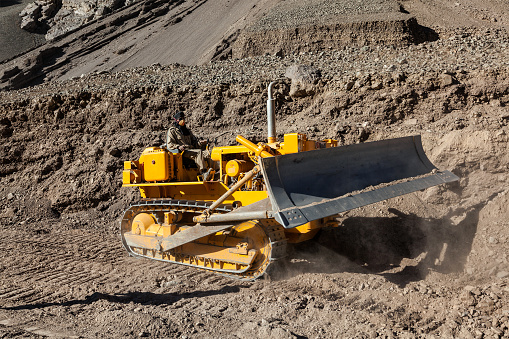 Ladakh, India - September 10, 2011: Bulldozer doing road constractuion on Srinagar - Leh National Highway 1 in Himalayas. Ladakh, Jammu and Kashmir, India