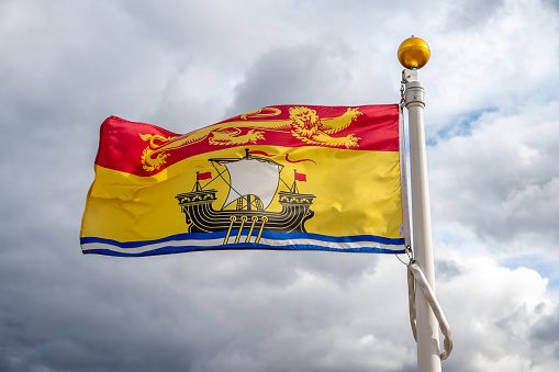 Flag of New Brunswick waiving on a cloudy Canadian day.