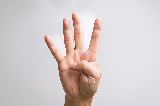 Hand showing four fingers. On white background.