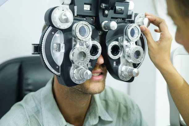 Man having eye test using phoropter. Smart handsome man having eye test, visual examination, check by a professional optician using clinical testing machine phoropter for making new eyeglasses at optic store. ophthalmologist photos stock pictures, royalty-free photos & images