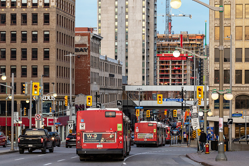 Ottawa, Canada - November 5, 2022: Busy traffic on Rideau street in downtown district. Cityscape with buildings, intersection, traffic lights, buses on the road and walking people.