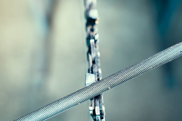 A round file sharpens a saw chain on a chainsaw bar close-up on a blurred background