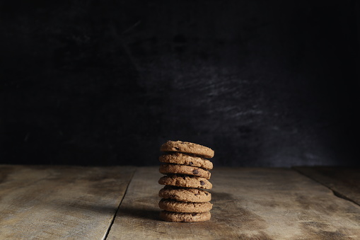stack of chocolate cookies on wooden table on black background