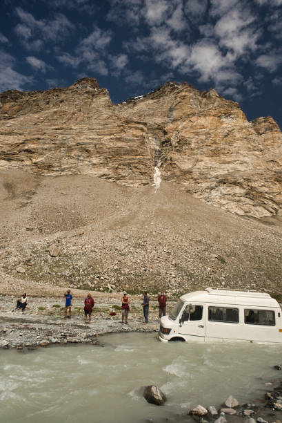 Tourist van partially submerged and stranded while attempting to cross a high mountain river during daytime stock photo