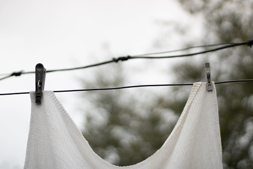 white waffle towel hanging on an iron wire pinned on the street