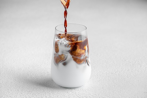 A closeup of a glass cup with an iced latte on white background
