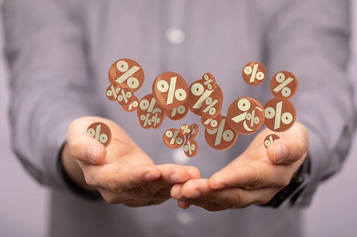 The 3D rendered brown percentage icons hovering over a person's hand on the background