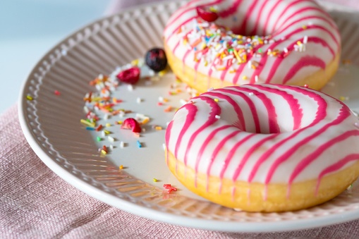 White pink frosted donuts on the plate