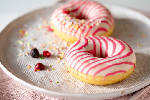 White pink frosted donuts on the plate