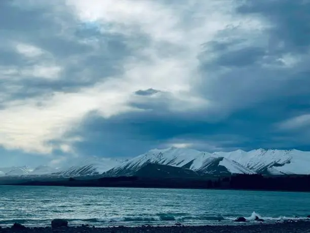 Photo of Scenic shot of a frozen sea in front of the snowy mountains under the clouded sky