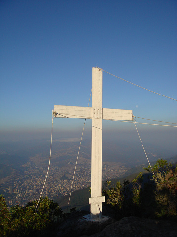 A vertical shot of a white cross on the top of the mountain in Parque Nacional El Avila, Venezuela