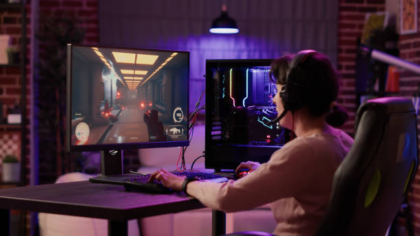 gamer-mädchen, das pc-setup verwendet, spielt multiplayer-ego-shooter, der über das headset spricht, während er das gameplay erklärt - multiplayer stock-fotos und bilder