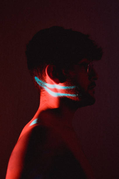 istock Young Hispanic artistic man with glasses posing in a dark room with a projector light on his face 1441837227