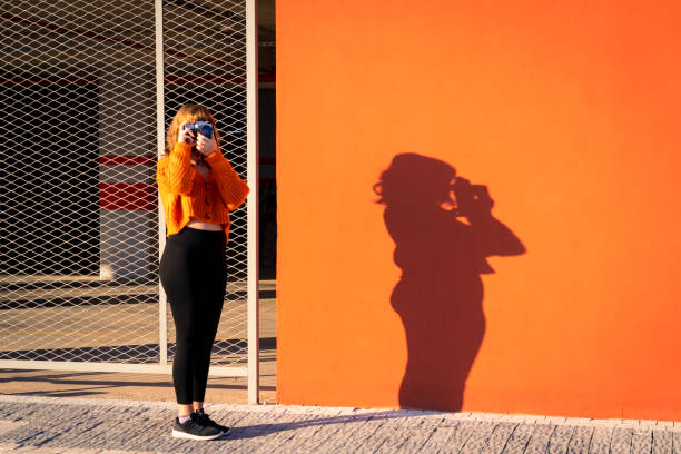 A woman walking past an orange wall stock photo