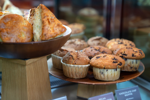 Close-up shot of fresh muffins and scones displayed in food shelf at bakery