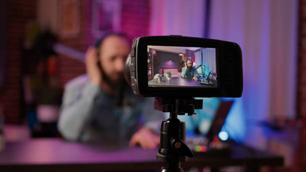 istock Selective focus on digital video camera screen recording male vlogger with headphones talking at microphone 1441838064