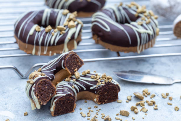 istock Closeup shot of a halved appetizing chocolate-covered raw donuts with nuts sprinkles 1441838986