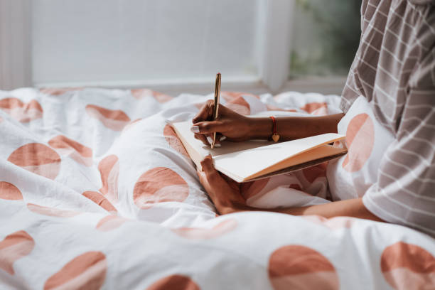 istock Closeup of a young African female writing notes while sitting on bed 1441839360