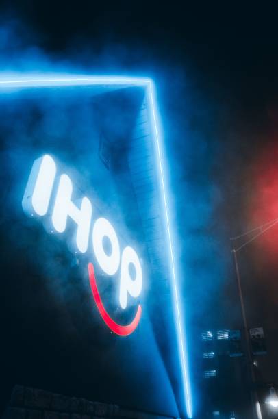 Low angle shot of a blue neon light sign of a multinational pancake house, at night Silver spring, United States – November 15, 2022: A low angle shot of a blue neon light sign of a multinational pancake house, with neon lights on the roof edges, at night Ihop stock pictures, royalty-free photos & images