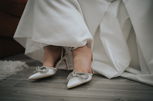 A closeup shot of a bride's shoes with bows