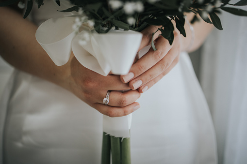 A bride wearing a wedding ring and holding her bouquet of flowers