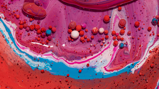 An abstract background of mixed red, white, and pink oily paints