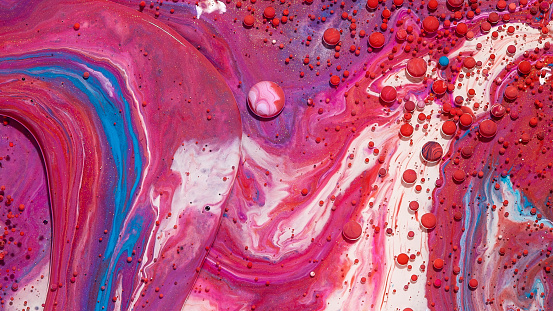 An abstract background of mixed red, white, and pink oily paints