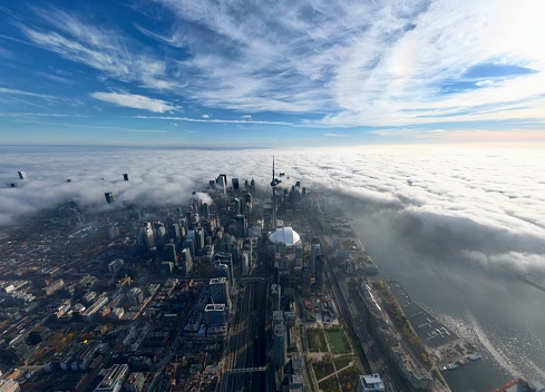 Toronto, Canada – November 03, 2022: A cityscape with the CN Tower in dense fog on the horizon in Toronto with cloudy sky