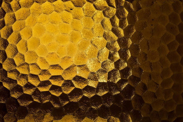 istock Abstract yellow coloured honeycomb shaped backlit glass background 1441840659