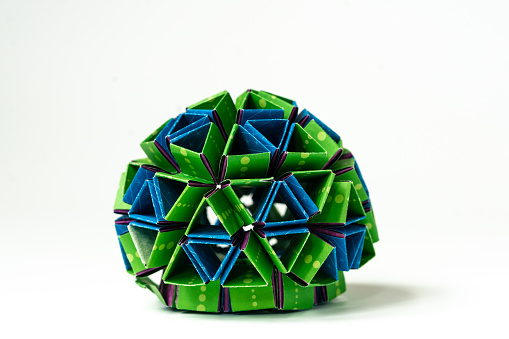 A circular blue and green origami sculpture isolated on a white background