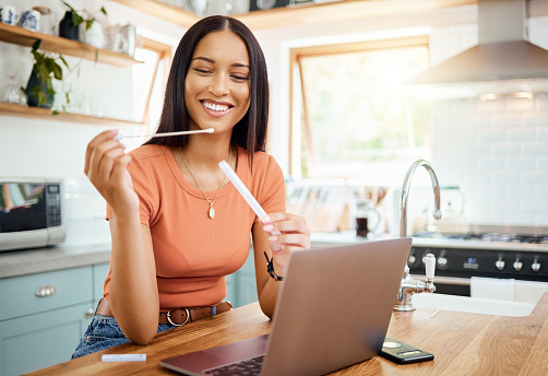 Home covid test, woman at table check healthcare and digital innovation technology. Online telehealth patient with medical pcr kit in hand, happy smile with rapid antigen and corona virus infection