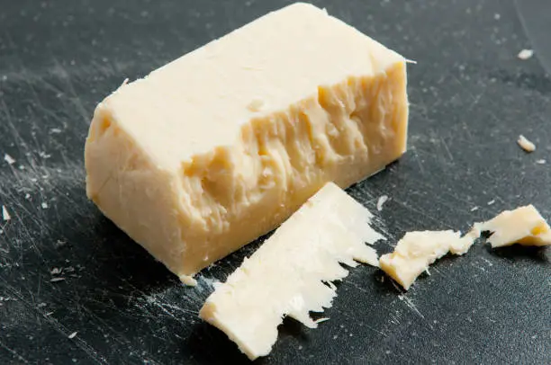 block of aged white cheddar cheese crumbling