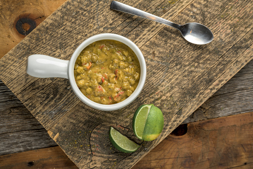 A top view of appetizing pumpkin cream-soup with seeds and lime on a wooden board