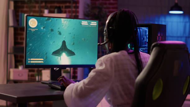 istock Over shoulder view of african american gamer girl playing space shooter simulation using pc gaming setup 1441842641