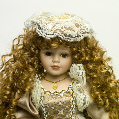 a closeup of a vintage Doll with beautiful golden tresses on a white background