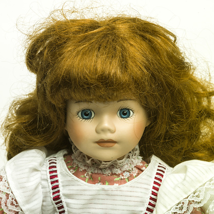 a closeup shot of a vintage doll with blue eyes on the white background