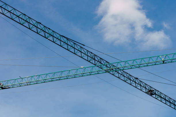 A low angle of jib cranes under a clear sky background