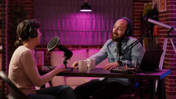 istock Man having casual conversation with woman in internet broadcast using professional microphone 1441844915