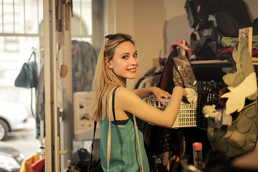 A shallow focus of a young blonde woman smiling in a vintage thrift store