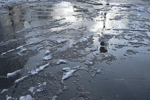 A high angle shot of melting snow on the street under the sunligh