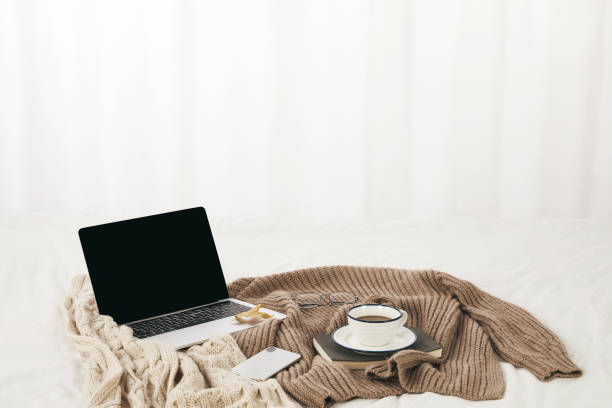 istock Closeup of a modern laptop on knitted sweaters with a cup of coffee on a notepad on them 1441846949